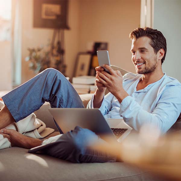 Enspannter Mann auf dem Sofa mit einem Handy in der Hand